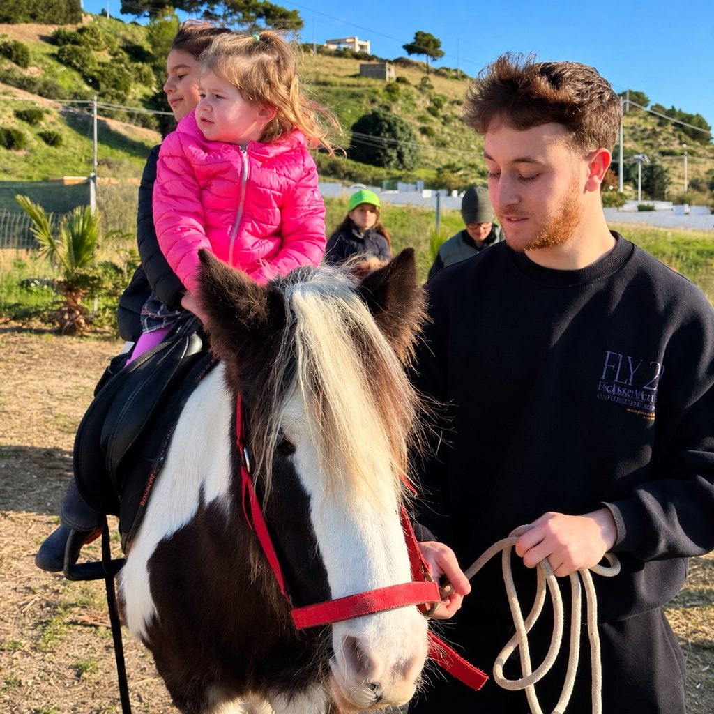 Una bambina sul pony, accompagnata a mano